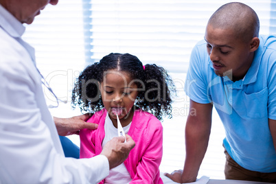 Doctor checking temperature of girl using thermometer