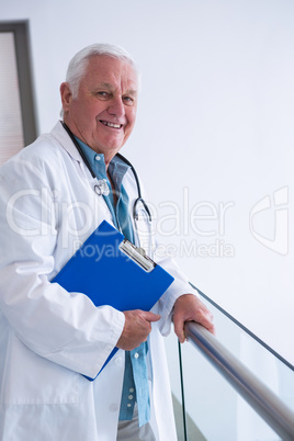 Doctor holding clipboard in the passageway at hospital
