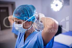 Female nurse tying surgical mask in operation theater