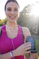 Smiling female jogger listening to music on mobile phone