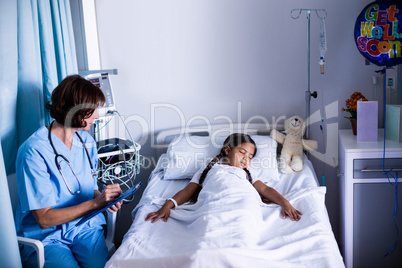 Doctor writing on clipboard while looking at patient