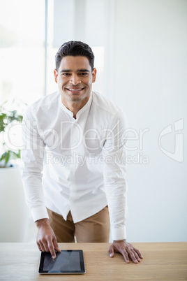 Smiling business executive using digital tablet at desk in office