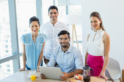 Portrait of smiling business colleagues discussing over laptop