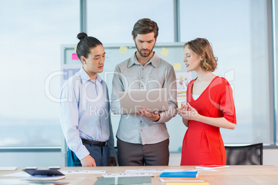 Business executives discussing over laptop in conference room