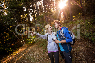 Hiking couple holding a compass and pointing forward