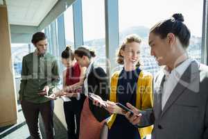 Business executives smiling while using electronic devices