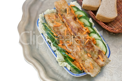 Fried fish with vegetables in a ceramic dish.