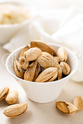 Almond nuts in a bowl on white background, healthy eating