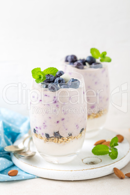 Greek yogurt or blueberry parfait with fresh berries and almond nuts on white background, healthy eating