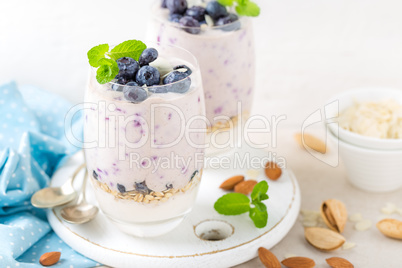 Greek yogurt or blueberry parfait with fresh berries and almond nuts on white background, healthy eating