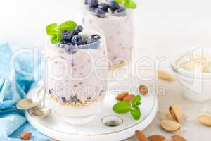 Greek yogurt or blueberry parfait with fresh berries and almond nuts on white background, healthy eating