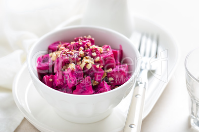 Beet vegetable salad with yogurt and walnuts in a bowl on white background