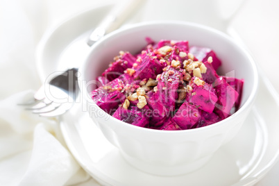 Beet vegetable salad with yogurt and walnuts in a bowl on white background
