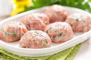 Raw meatballs on white plate, cooking in kitchen