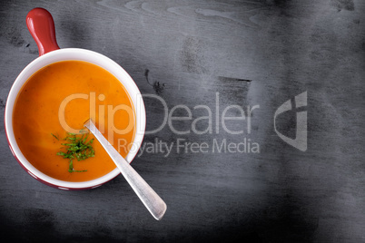 Pumpkin creme soup with a spoon served on a table.