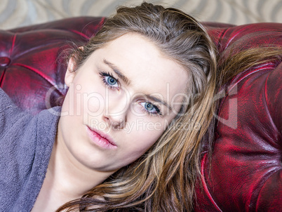 Woman is lying on the sofa and looks expressionless