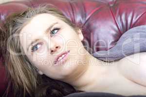 Woman is lying on the sofa and looks expressionless