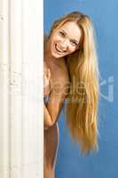 Blond woman with long hair hides behind pillar