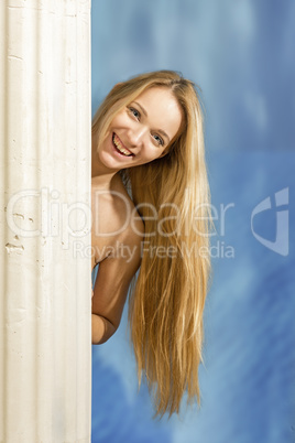 Blond woman with long hair hides behind pillar