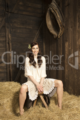 Young woman with horse saddle in the barn