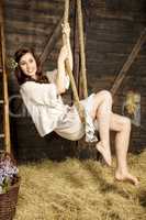 Young woman swings on a rope in the barn