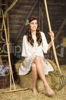 Young woman with fork in the barn