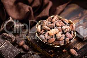 Cocoa beans and chocolate on wooden background