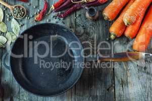 Black empty cast-iron frying pan among vegetables