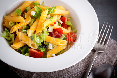 Pasta salad with fresh greenery and tomatos.