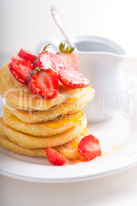 Stack of sweet pancakes with strawberry and honey.