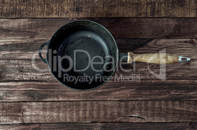 Black cast-iron frying pan on a brown wooden surface