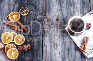 cup of hot coffee with orange slices on a gray wooden surface