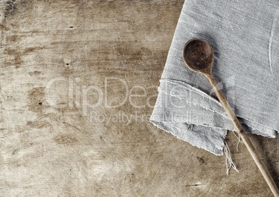 Brown wooden background with a wooden spoon and a gray tableclot