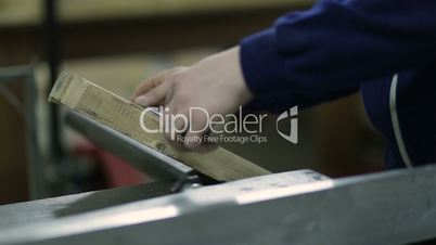 Carpenter measures length of plank before sawing