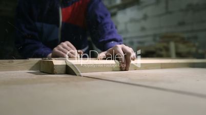 Carpenter cutting wooden plank with table saw