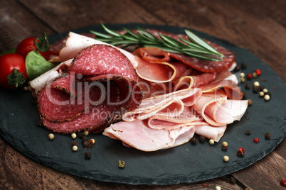 Food tray with delicious salami, pieces of sliced ham, sausage, tomatoes, salad and vegetable - Meat platter with selection