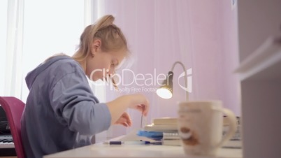 Teen girl draws a circle on the sheet using a pair compasses