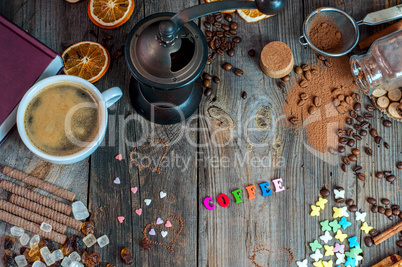 cup of black coffee with sweets and spices on a gray wooden surf