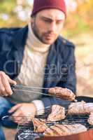 Man cooking meat on charcoal grill