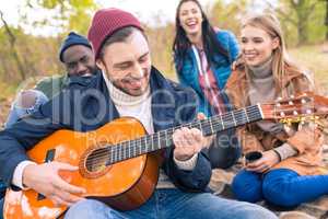 Friends enjoying guitar in autumn park