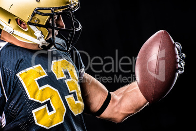 Muscular football player looking at ball