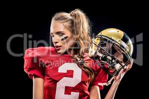 Female football player posing with helmet