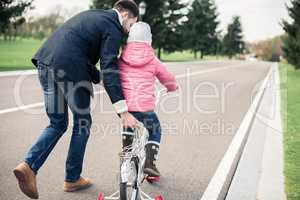 Father teaching daughter to ride bicycle