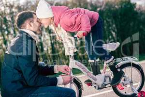 Father checking bicycle of little daughter