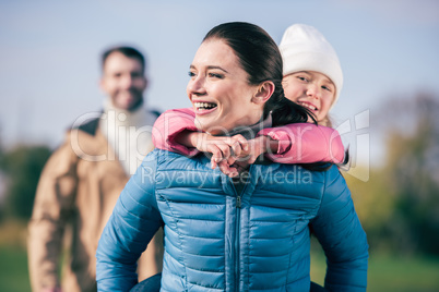 Cheerful mother piggybacking little daughter