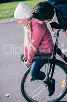 Father carrying smiling daughter on bicycle