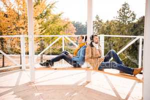 Young couple sitting on bench in headphones