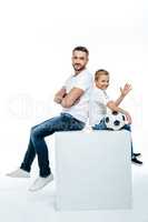 Father and son sitting with soccer ball