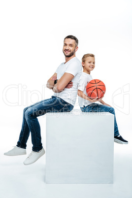 Father and son sitting with basketball ball