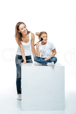 Mother looking at daughter with makeup brush